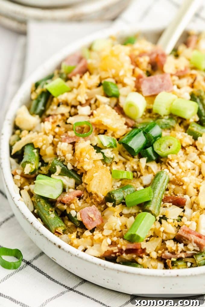 Pineapple Cauliflower Rice in a bowl, showing the vibrant colors of pineapple, cauliflower, bacon, and green beans.