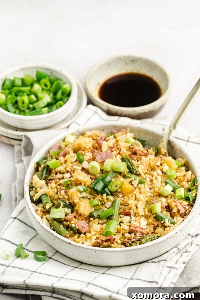 Close-up of Pineapple Cauliflower Rice, showing finely chopped bacon and pineapple pieces mixed with cauliflower and green beans.