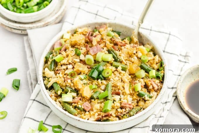 A serving of Pineapple Cauliflower Rice in a white bowl, garnished with fresh green onions.