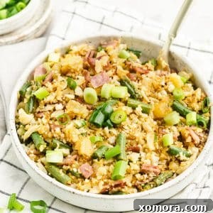 A dish of Pineapple Cauliflower Rice with a serving spoon.