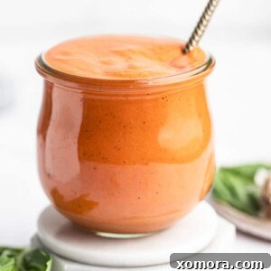 A bowl of creamy roasted red pepper sauce garnished with fresh basil.