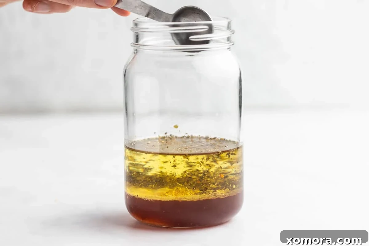 A hand shaking a jar of freshly prepared homemade Italian dressing.