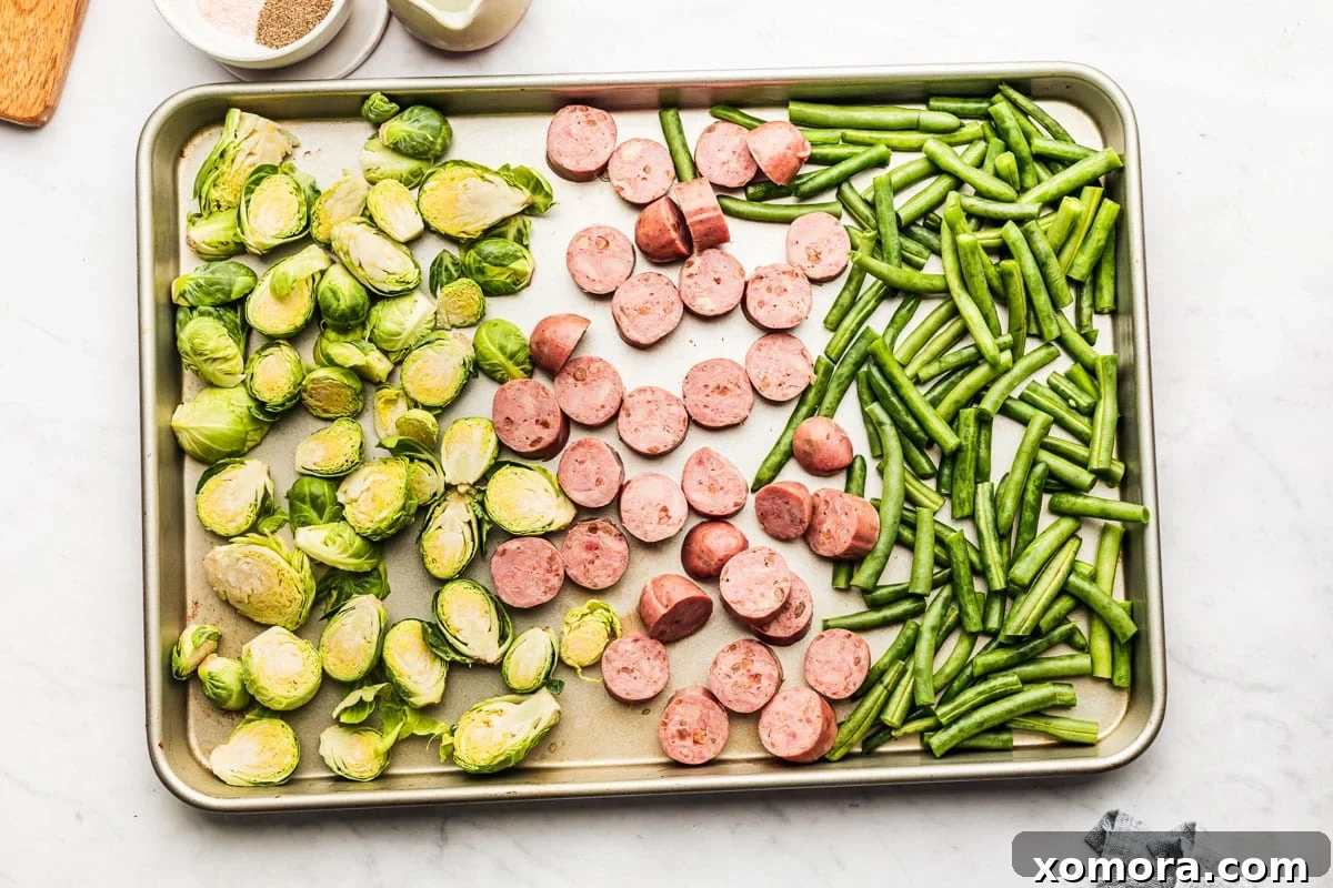 One-Pan Sausage and Roasted Vegetables 4 Assortment of raw ingredients for sheet pan dinner: sausage, green beans, Brussels sprouts, oil, and seasonings.