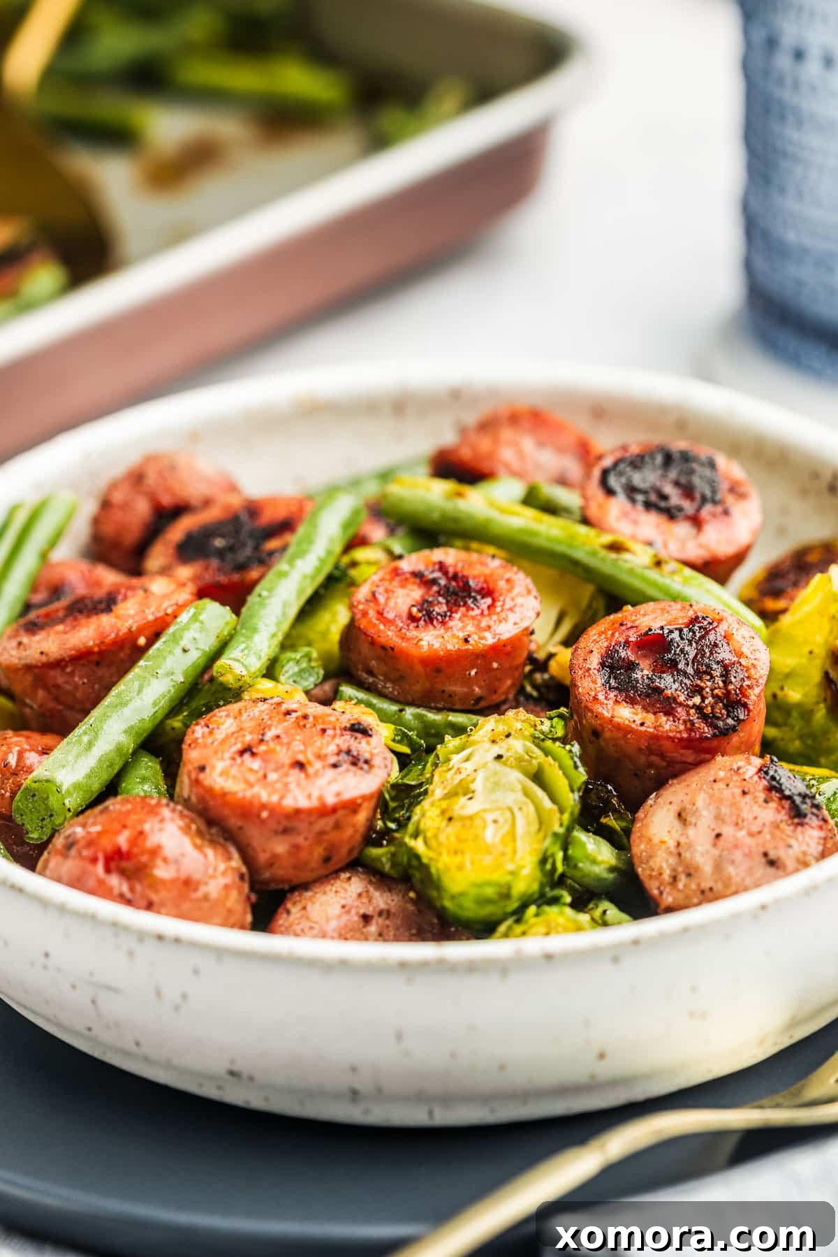 One-Pan Sausage and Roasted Vegetables 5 A serving of roasted sausage and vegetables on a plate, garnished with fresh herbs.