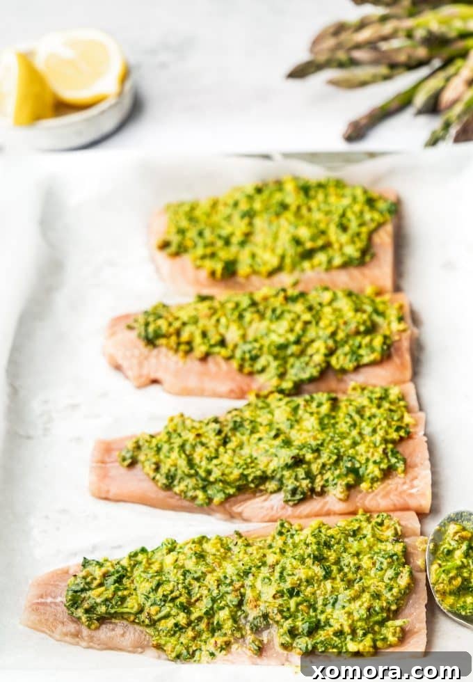 Close-up of a single pistachio herb crusted salmon fillet with roasted asparagus, showing the textured crust and tender salmon.