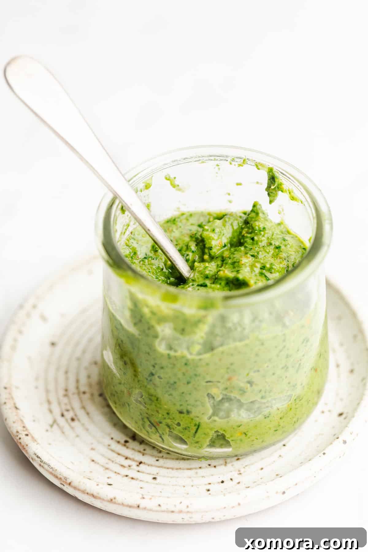 A serving of pasta tossed with the vibrant dairy-free pistachio lemon pesto, garnished with fresh basil leaves.