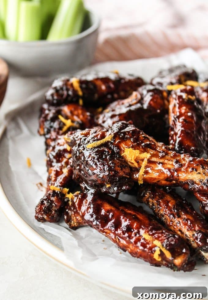 Zesty Orange Balsamic Glazed Wings 2 Close-up of freshly baked sticky orange balsamic wings on a platter, garnished with orange zest.