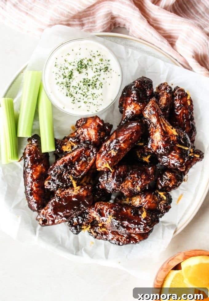Zesty Orange Balsamic Glazed Wings 3 A close-up of a single sticky orange balsamic chicken wing, glistening with sauce and a hint of orange zest.