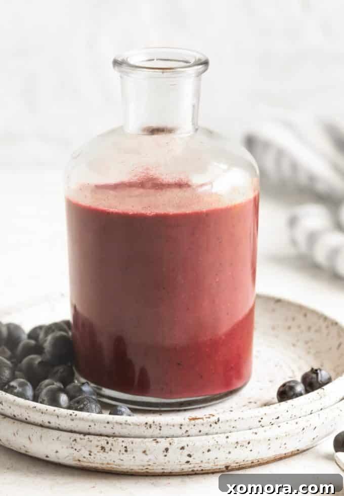 Blueberry Bliss Dressing 2 Vibrant homemade blueberry dressing in a glass jar, ready to be poured over a fresh salad, emphasizing its beautiful color and smooth texture.