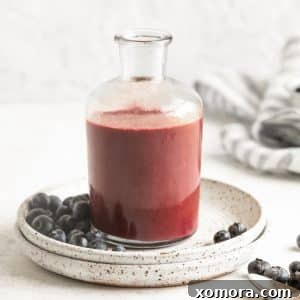 Freshly blended blueberry dressing in a glass container, garnished with a few whole blueberries, showcasing its readiness.