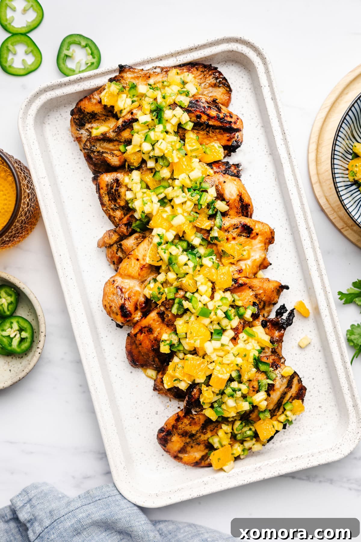 Exotic Flame-Grilled Chicken with Tropical Fruit Salsa 2 Beautifully grilled chicken breast adorned with a vibrant tropical salsa featuring diced pineapple, orange segments, and fresh cilantro. A perfect summer meal.
