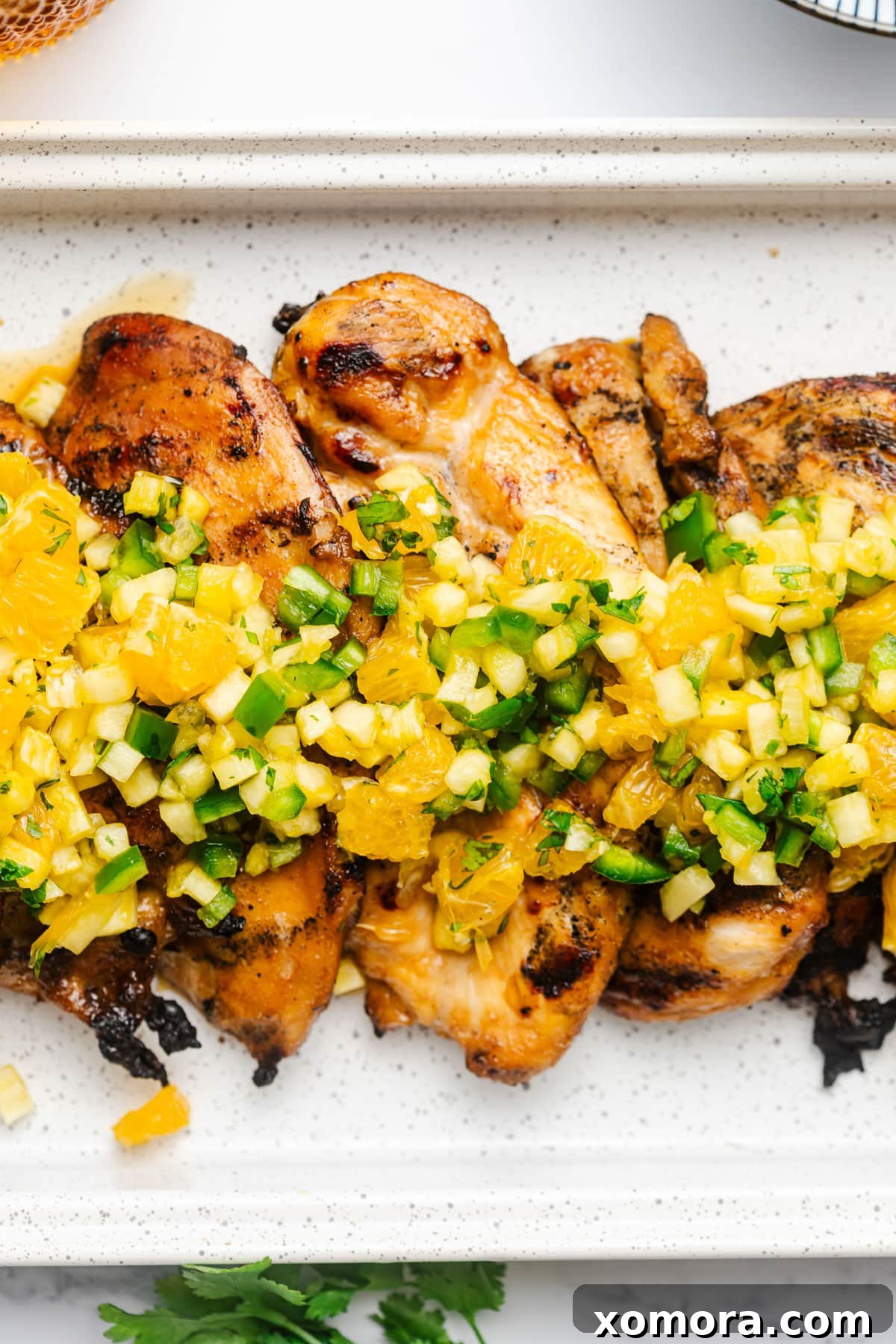 Exotic Flame-Grilled Chicken with Tropical Fruit Salsa 6 Overhead shot of multiple plates featuring tropical salsa grilled chicken, garnished with fresh salsa, on a rustic wooden table, perfect for sharing.