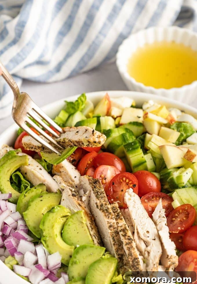 A serving of Lemon Chicken Cobb Salad showcasing a beautiful cross-section of perfectly cooked chicken, sliced avocado, hard-boiled eggs, and vibrant vegetables.