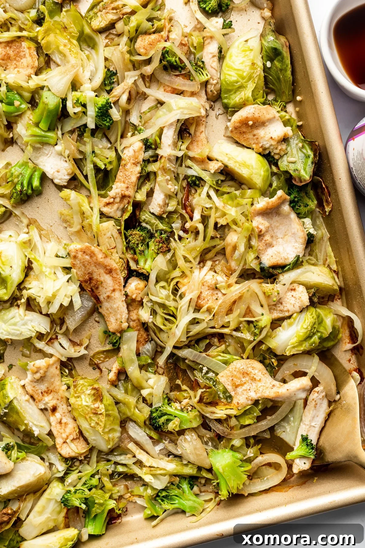 A vibrant sheet pan chicken and cabbage stir fry, fresh out of the oven, with tender chicken strips and caramelized vegetables.
