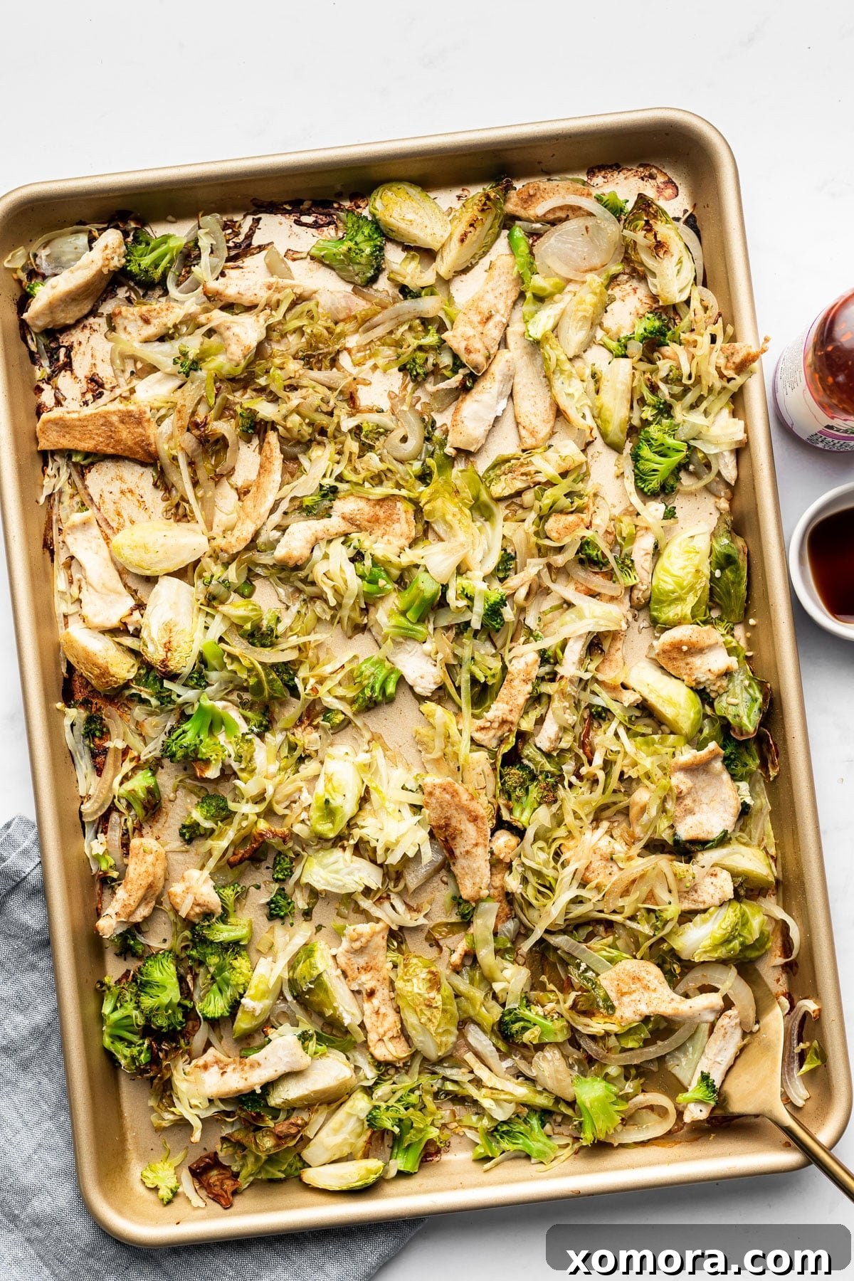 A serving of sheet pan chicken and cabbage stir fry topped with fresh green onions and sriracha.