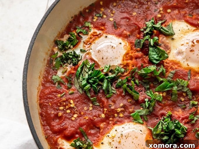 Close-up of a perfectly poached egg in Shakshuka, showing the firm white and a vibrant runny yolk mixing with the tomato sauce.