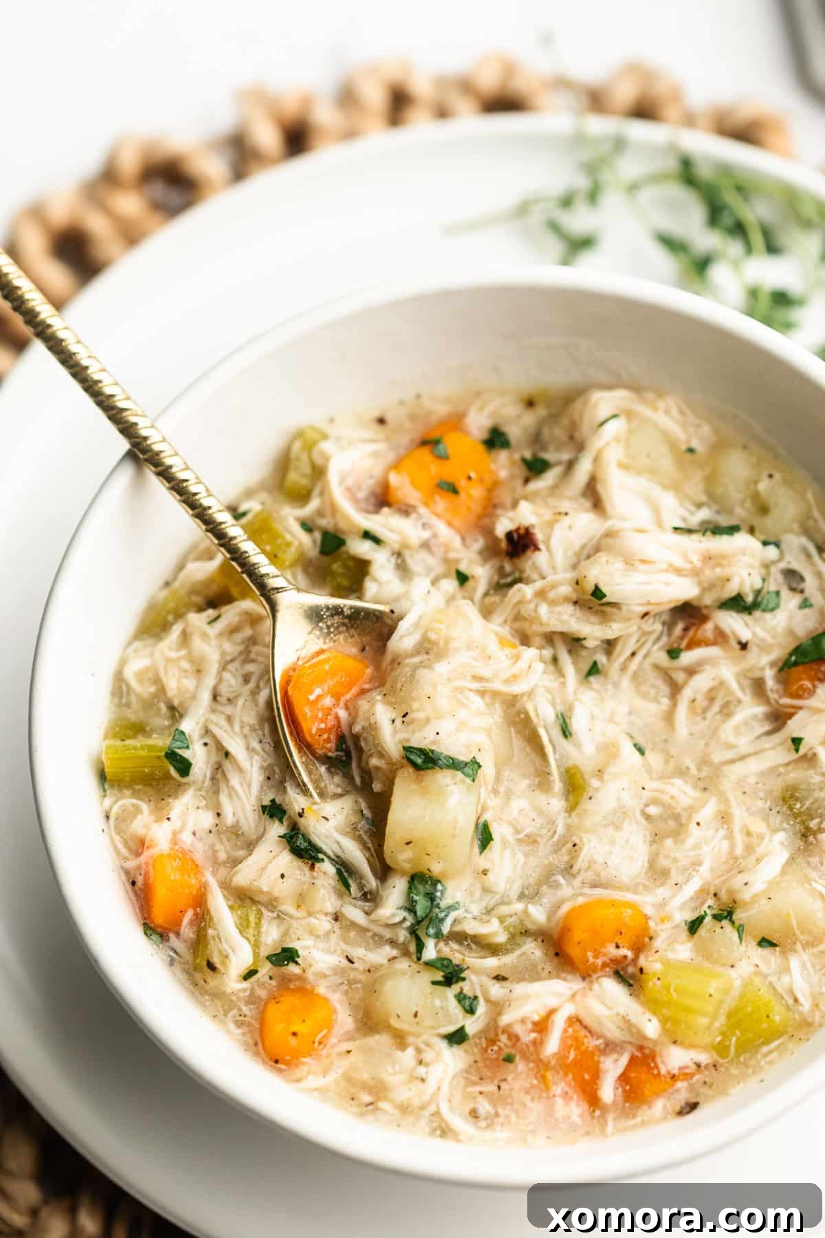 Comforting Crockpot Chicken Stew 6 A wooden spoon scooping out a portion of slow cooker chicken stew from a pot.