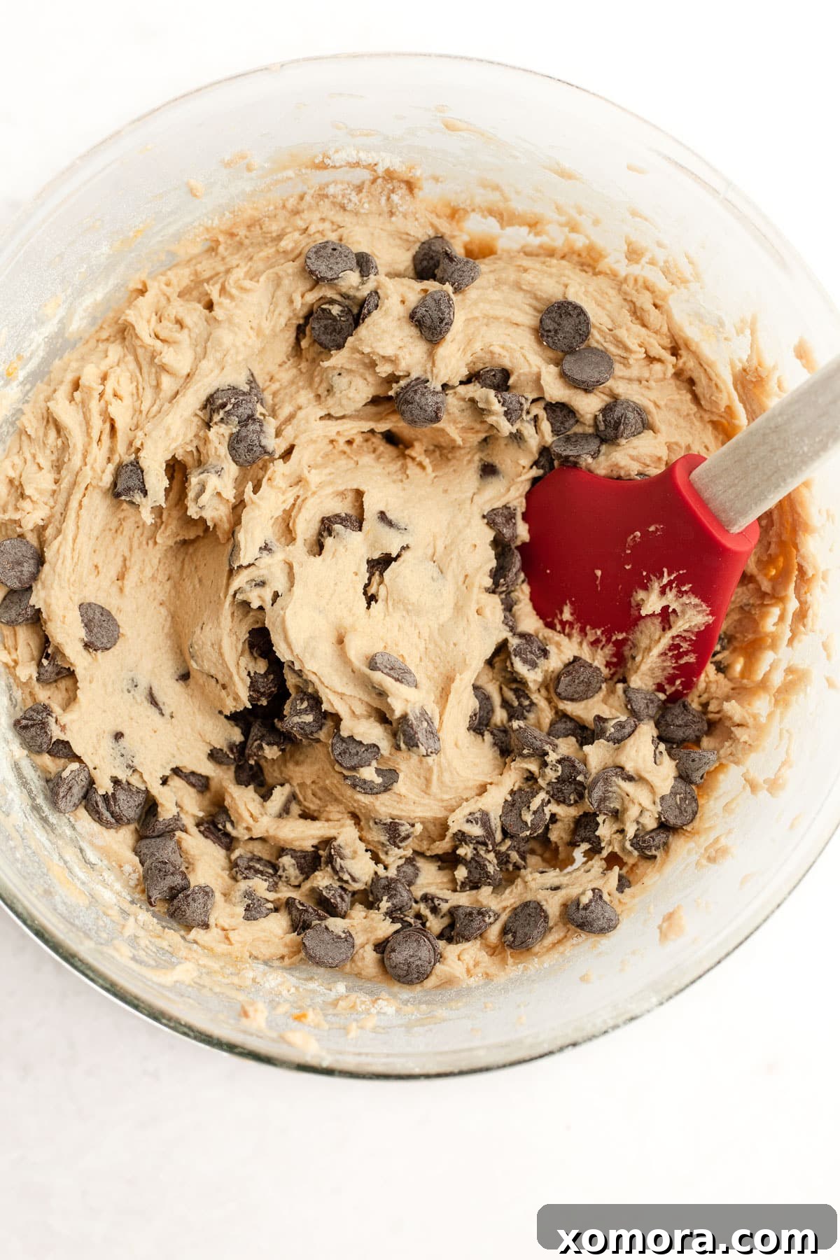Plant-Based Chocolate Chip Bliss 4 A hand reaching for a dairy-free chocolate chip cookie on a cooling rack.
