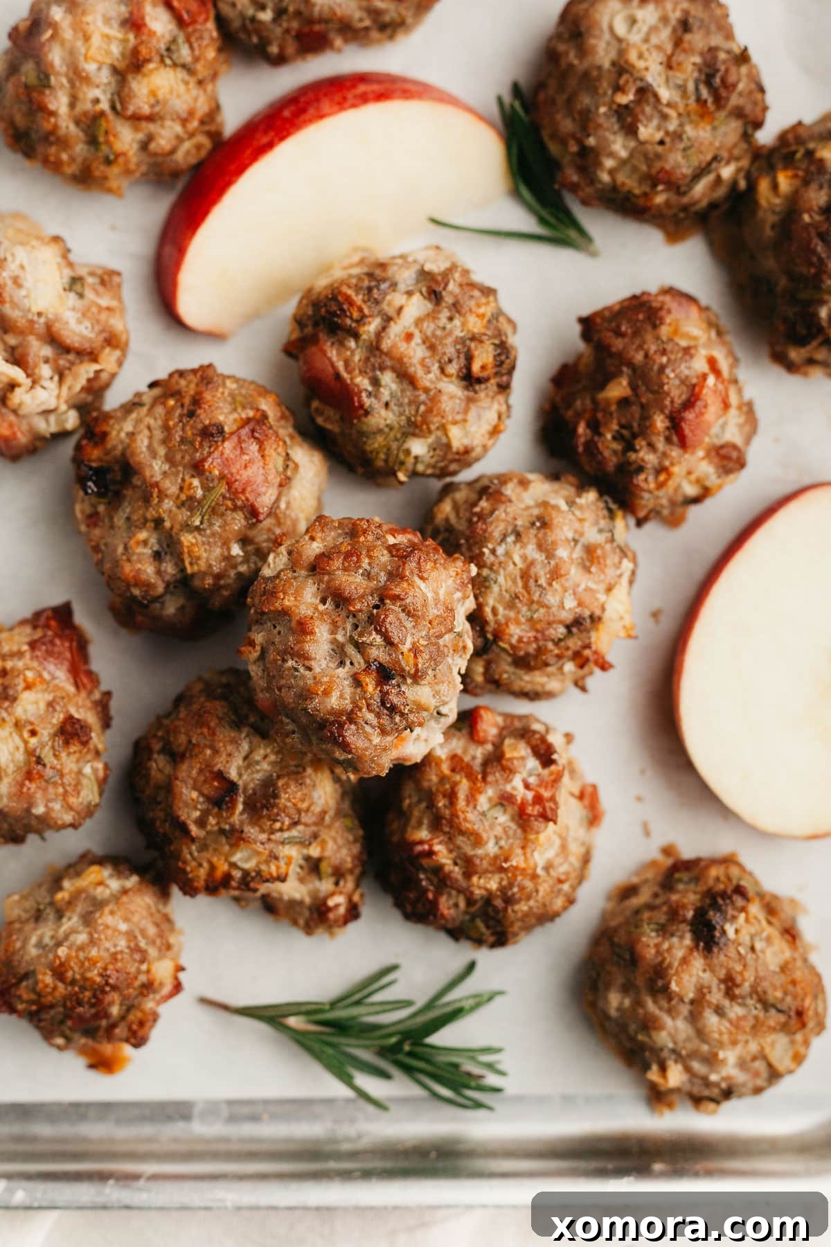 Close-up of perfectly baked turkey apple breakfast meatballs on a serving plate, garnished with fresh rosemary.