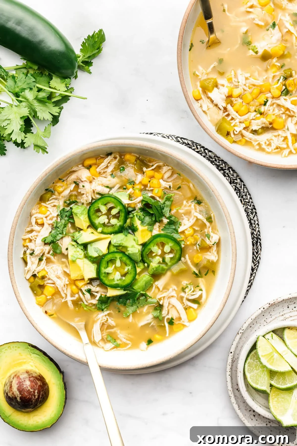 Zesty Salsa Verde Chicken Soup 2 A vibrant bowl of Salsa Verde Chicken Soup garnished with fresh cilantro and a lime wedge, ready to be enjoyed.