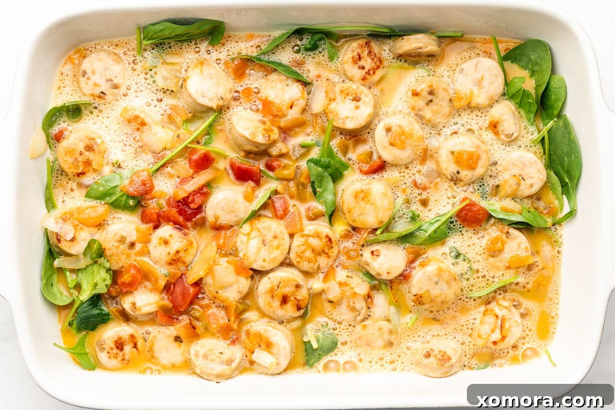 Ingredients for dairy-free chicken sausage breakfast casserole laid out, including chicken sausage, eggs, salsa, spinach, and shredded sweet potatoes.