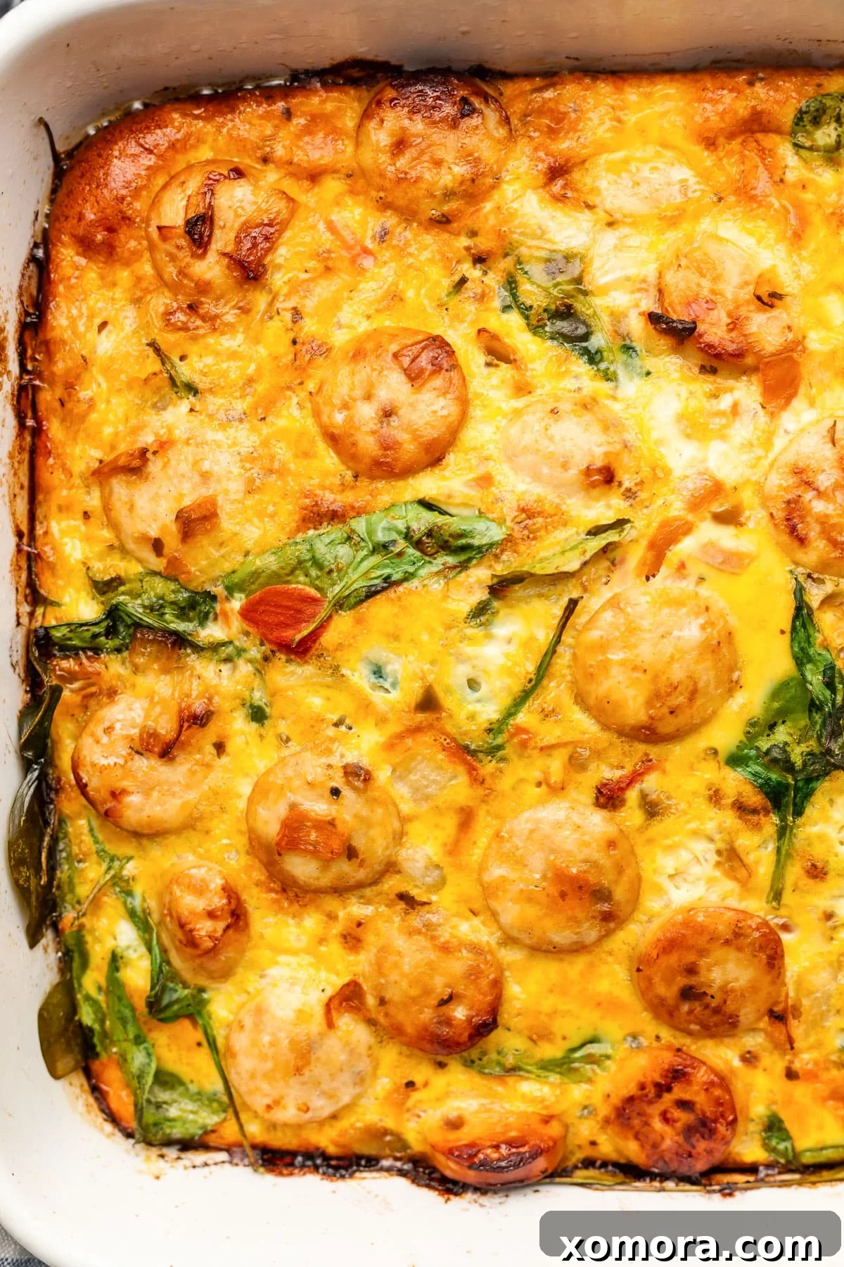 Cooked dairy-free chicken sausage breakfast casserole, still in the baking dish, garnished with fresh herbs and ready to be served.