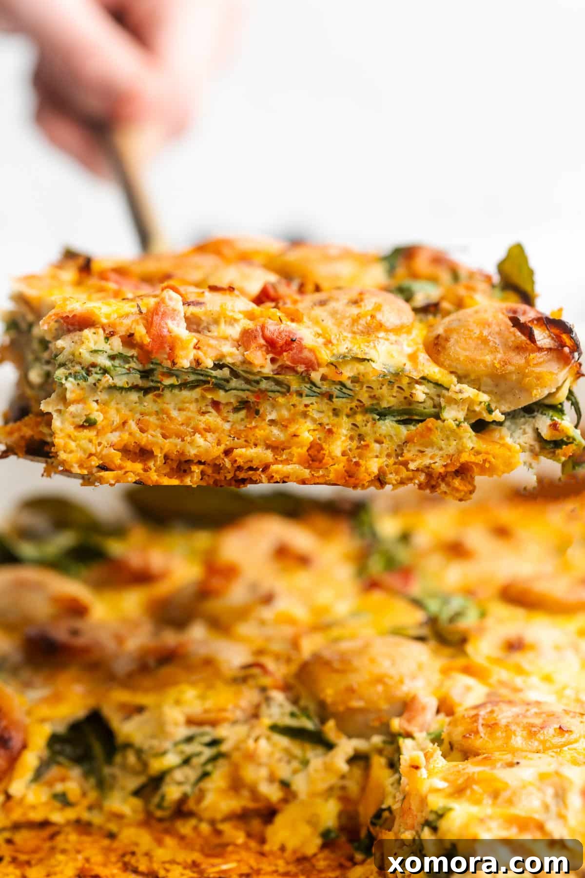 A close-up of a slice of dairy-free chicken sausage breakfast casserole, showcasing the layers and textures of the ingredients.