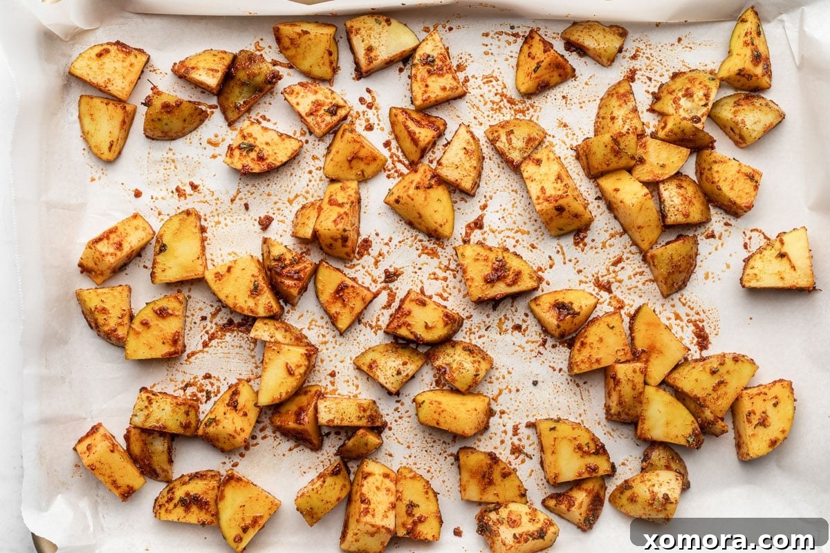 Golden Crispy Oven Potatoes 4 Roasted potatoes spread in a single layer on a parchment-lined baking sheet.