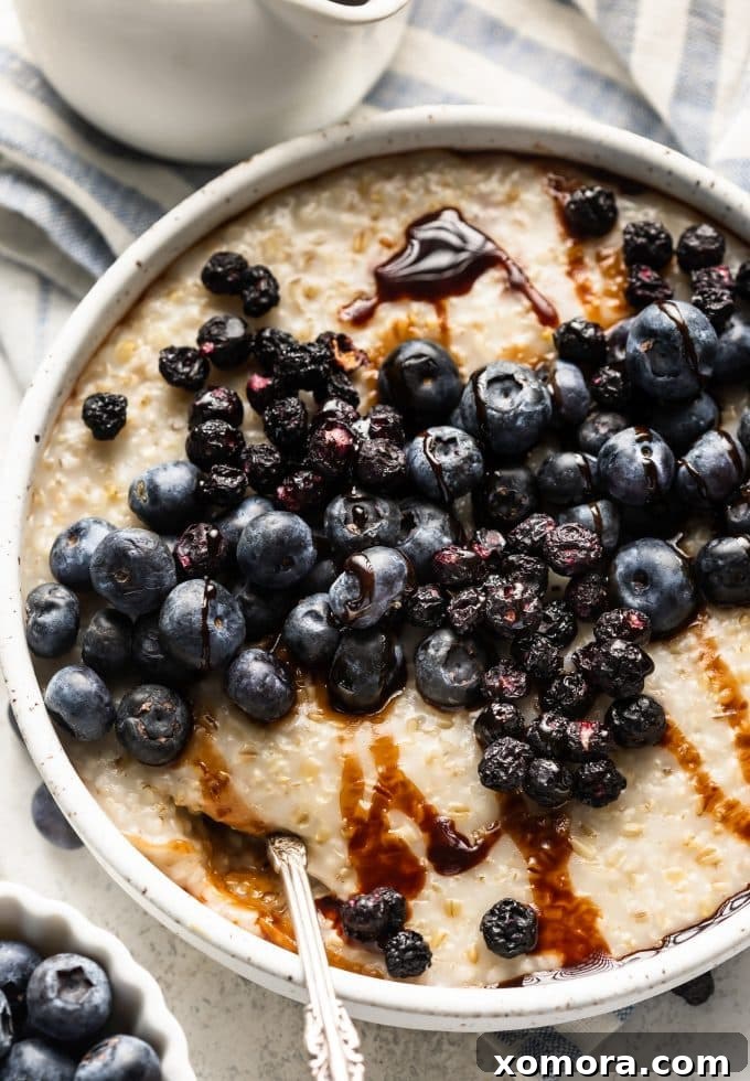 Close-up of creamy steel cut oats with fresh and freeze-dried blueberries, drizzled with date syrup.