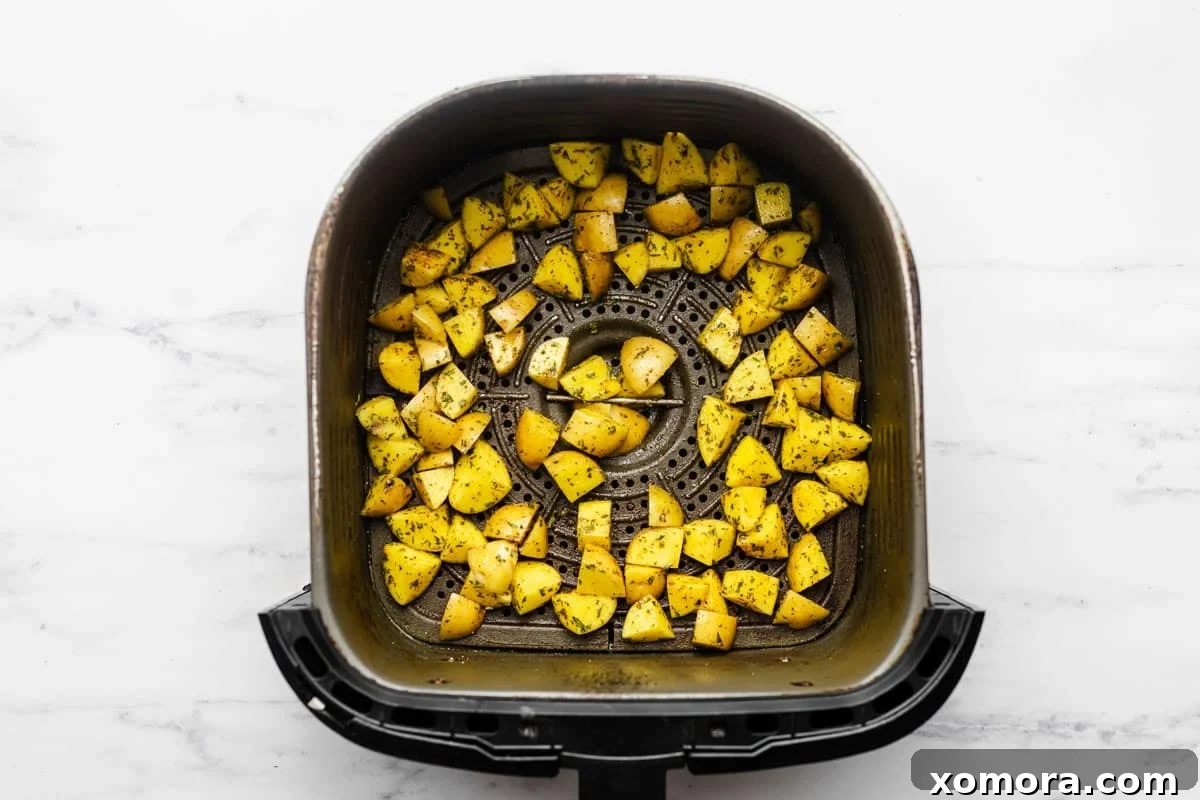 Golden Air Fryer Potato Bites 4 Diced potatoes being tossed in a bowl with olive oil and spices