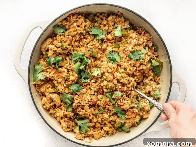 Fiesta Chicken Cauliflower Rice Skillet 3 Close-up shot of Mexican Chicken Fried Cauliflower Rice served in a bowl with a fork, showing texture and ingredients.