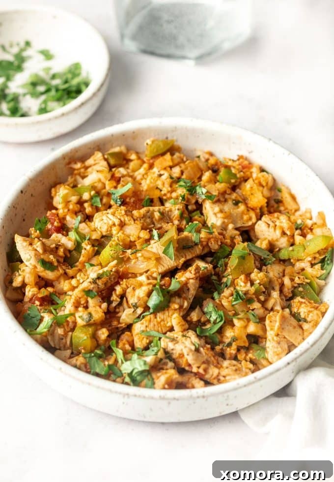 Fiesta Chicken Cauliflower Rice Skillet 4 A serving of Mexican Chicken Fried Cauliflower Rice topped with a dollop of guacamole and a sprinkle of cilantro.