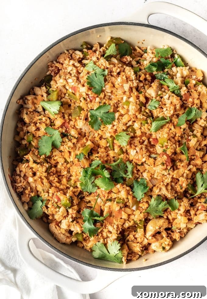 Fiesta Chicken Cauliflower Rice Skillet 5 Another overhead shot of Mexican Chicken Fried Cauliflower Rice in a bowl, with a spoon for serving.