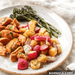 Close-up of a sheet pan dinner with marinated chicken, broccolini, parsnips, and roasted radishes.