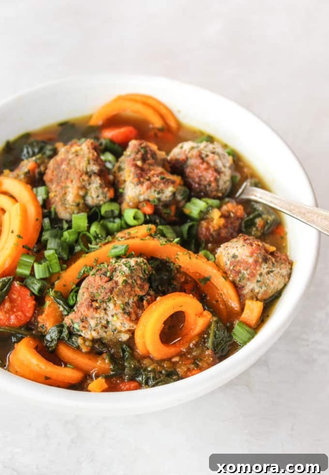A steaming bowl of comforting turkey meatball and butternut squash soup, garnished with fresh herbs, perfect for a healthy and satisfying meal.